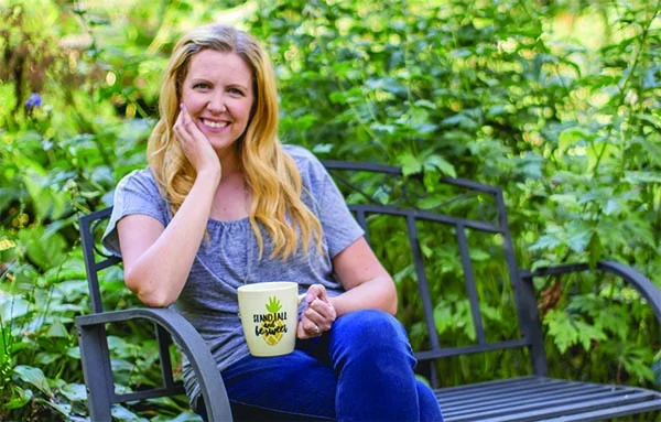 Erika Bragdon sitting on a bench drinking a drink out of her mug