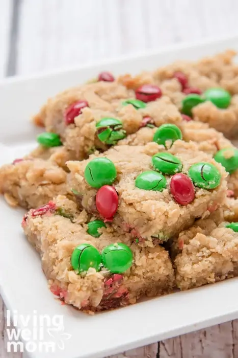 A stack of baked cookie bars with red and green m&m's on a serving platter.