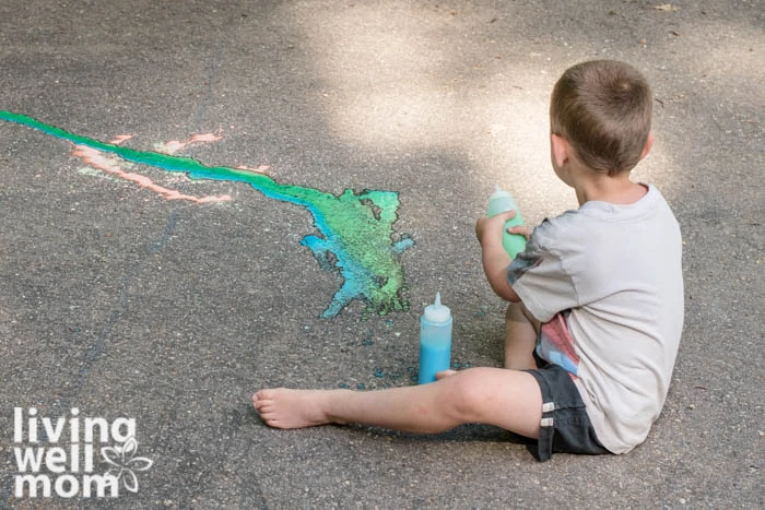 Young boy mixing blue and green sidewalk paint together