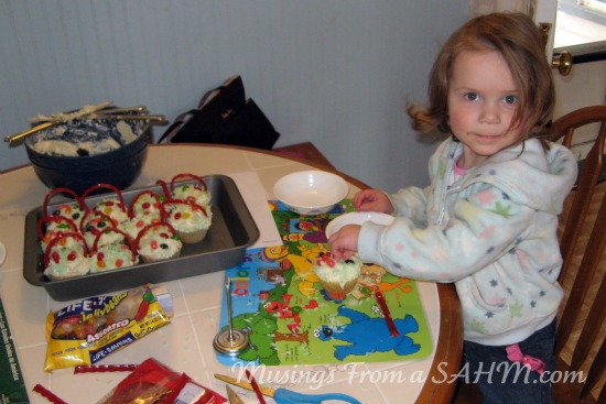 spring activities for kids - little girl putting candy on easter cupcakes