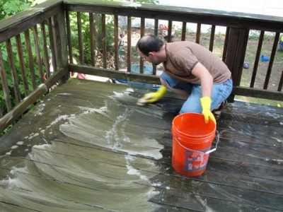 man scrubbing wooden deck with Thompson's Waterseal cleaner 