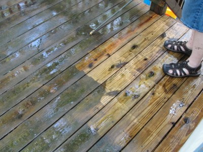 wooden deck boards partly clean partly dirty with man's feet