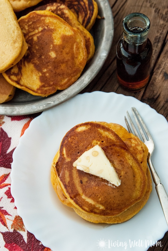 pumpkin spice pancakes with butter and maple syrup on a white plate