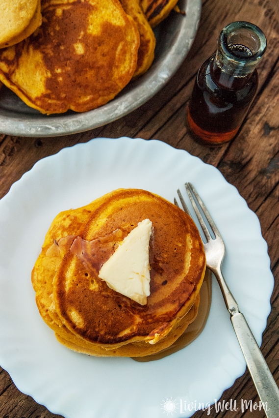 pumpkin spice pancakes with butter and maple syrup on a white plate