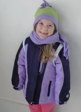 A little girl posing for a picture in snow gear