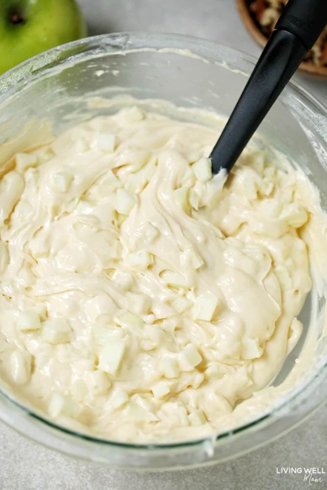 Chunks of granny smith apples being folded into apple coffee cake recipe batter. 