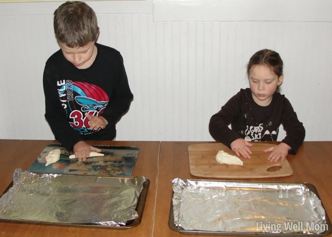 a little boy and girl forming shapes and letters with dough