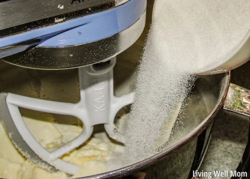 sugar being poured into butter in a bowl 