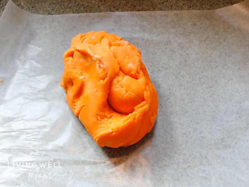 Lump of colorful, homemade playdough cooling on wax paper. 