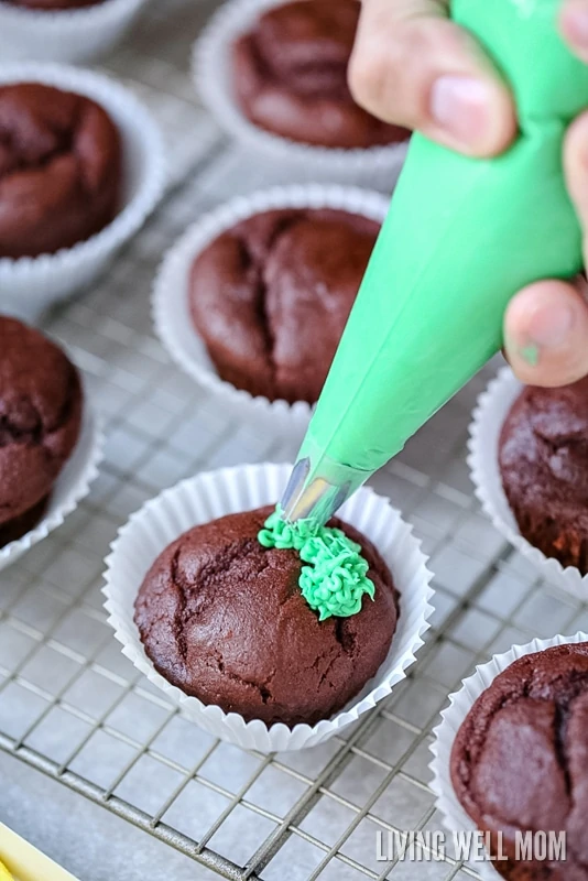 green frosting being put onto the cupcakes 