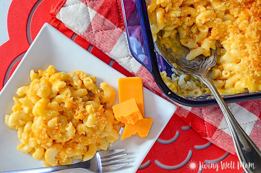 homemade mac and cheese for kids on a white plate with cheddar cheese and red background