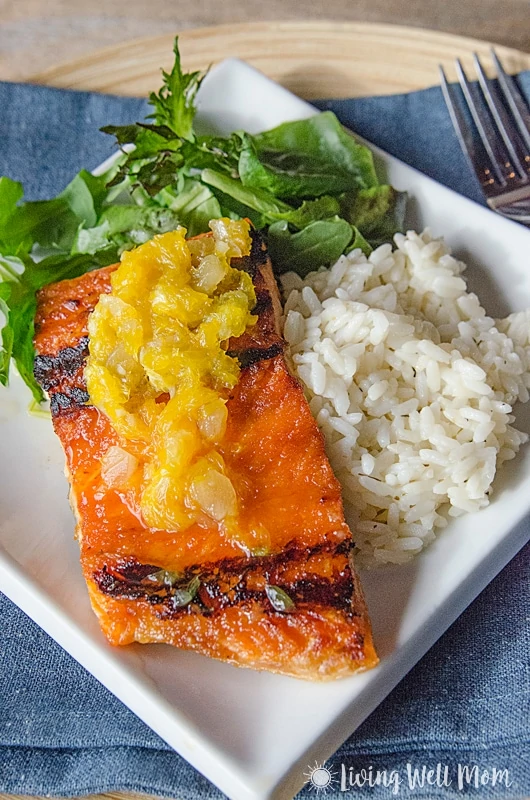 baked salmon with orange glaze on a white plate with greens and rice
