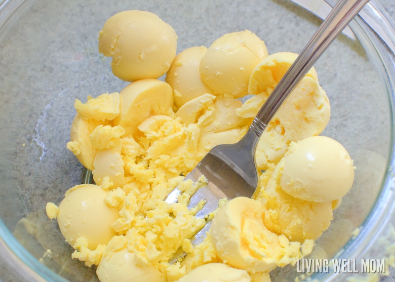 mashing hard boiled egg yolks in a bowl with fork