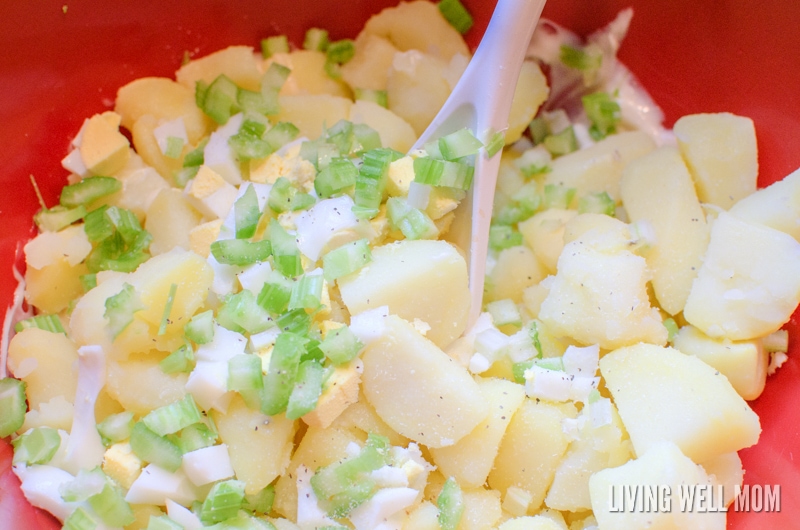 mixing cut cooked potatoes with celery and hard boiled eggs for potato salad