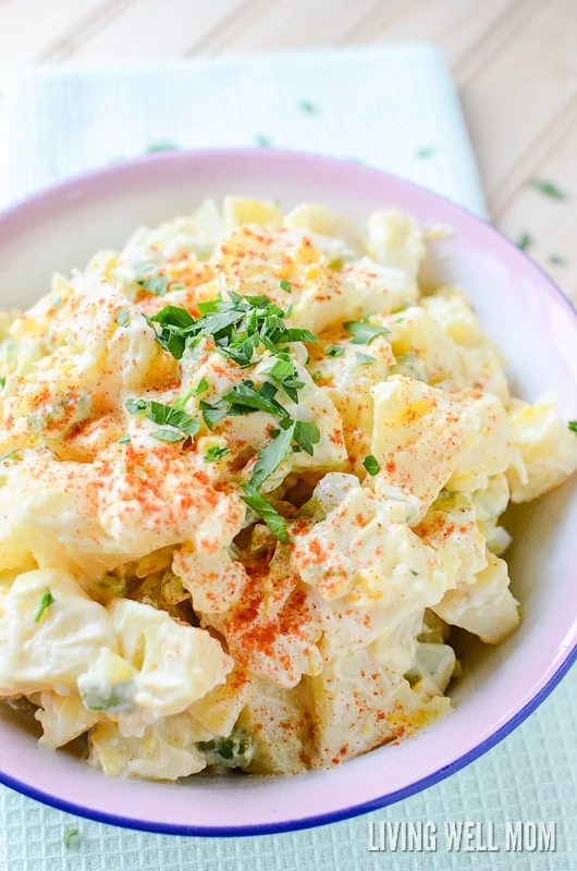 close up of homemade potato salad in a bowl topped with paprika and fresh herbs 