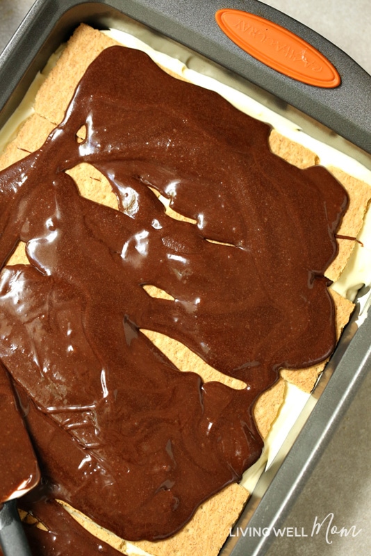 spreading chocolate frosting over graham crackers for chocolate eclair cake