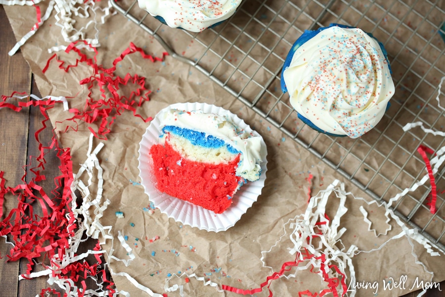 half of a red white blue patriotic cupcake on wrapper with other cupcakes on wire rack in background
