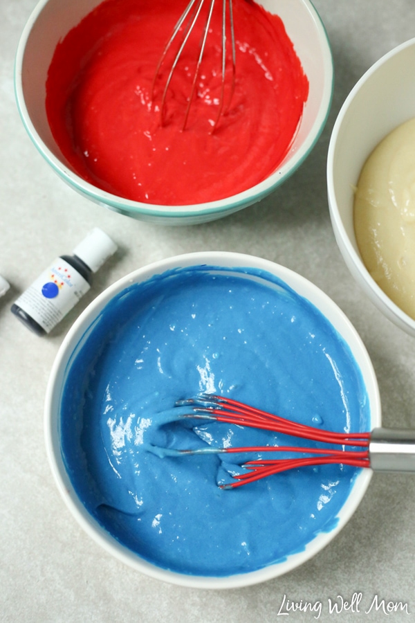 whisks in red white blue colored cake batter in bowls