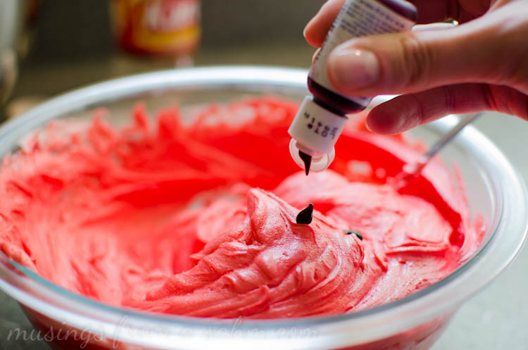 frosting in a bowl with food dye being added 