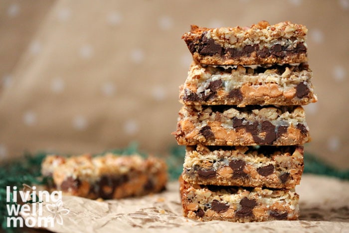 stack of magic cookie bars with beige spotted background and coconut flakes