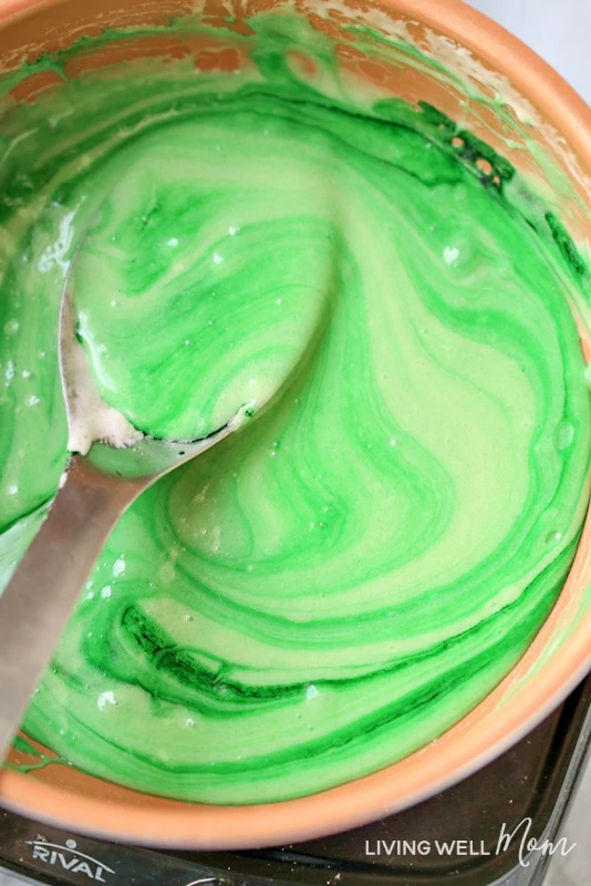 Stirring lime jello and green food coloring into melted butter and marshmallows 