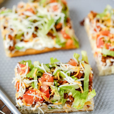 Taco Pizza is a great as an easy family dinner (you can even make it the night before) or a tasty appetizer. Kids love this recipe and the cream cheese/sour cream “sauce” and spicy taco flavor are a hit with adults too.