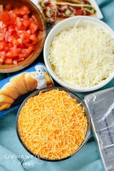 ingredients for taco pizza - 2 bowls of cheese, Pillsbury crescent rolls, and tomatoes. 