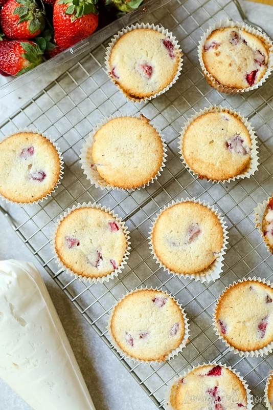 Baked strawberry cheesecake muffins on a cooling rack. 