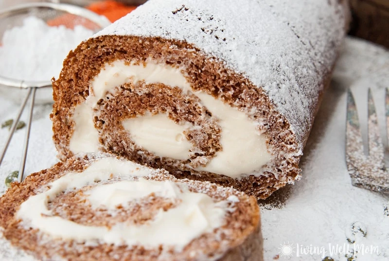 Pumpkin spice roll with a single slice cut, showing the cream cheese filling.
