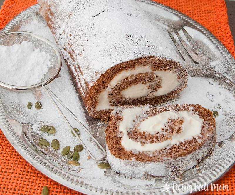 Sliced pumpkin spice roll on a silver platter with powdered sugar