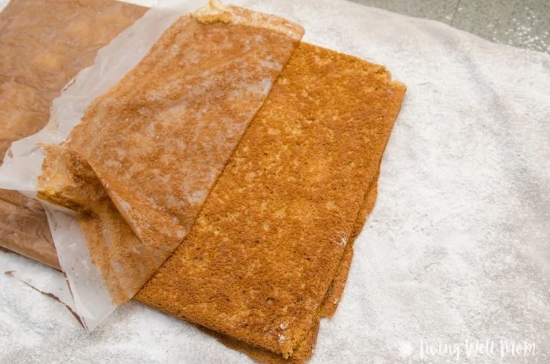 Gently peeling off the waxed paper from cake layer for a pumpkin spice roll recipe