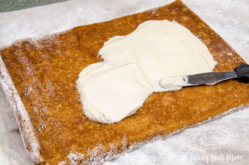Cream cheese filling being spread on a pumpkin roll