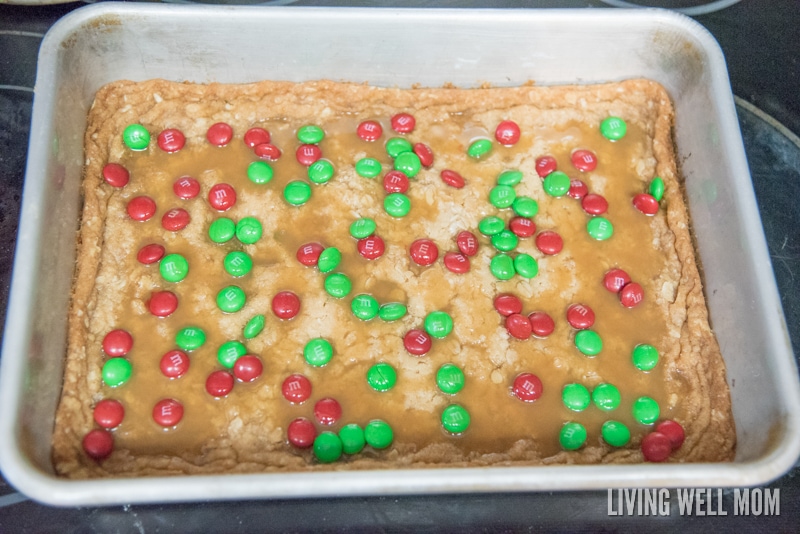 A baked cookie bar drizzled in caramel syrup and topped with milk chocolate candies. 