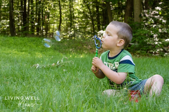 A boy blowing homemade bubble solution through a wand