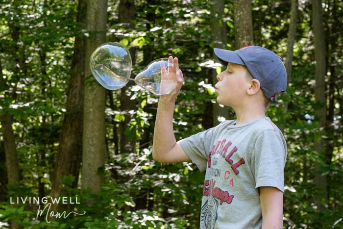 A child blowing homemade bubbles, using their hand as a wand.