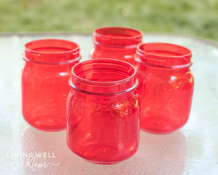 4 red plastic jars for bubble solution storage on an outdoor table.