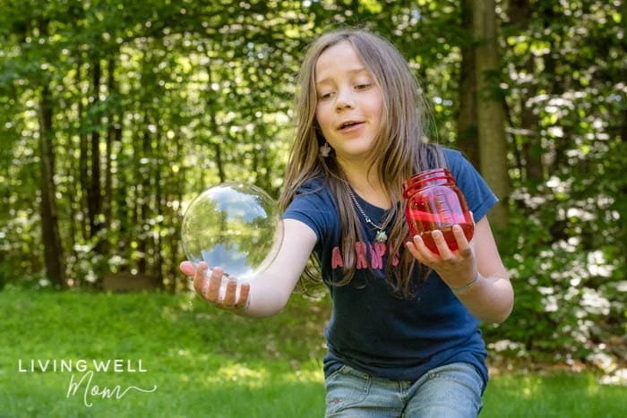 girl catching a giant bubble made from homemade bubble solution
