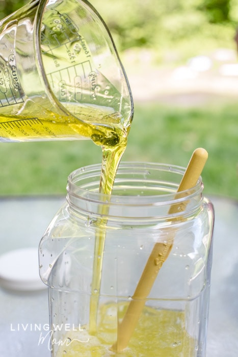 A cup of dish soap being mixed with water and corn syrup. 