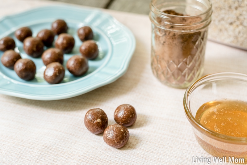 Completed no-bake protein balls with cacao powder and honey for sweetener, displayed on a blue plate on a table. 