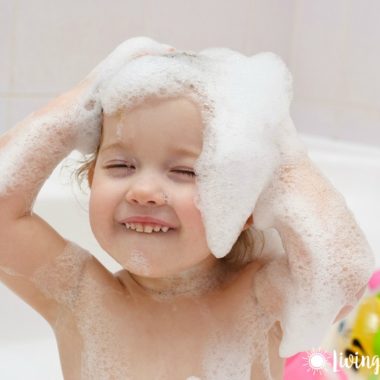 child with shampoo sudsy hair smiling in bathtub
