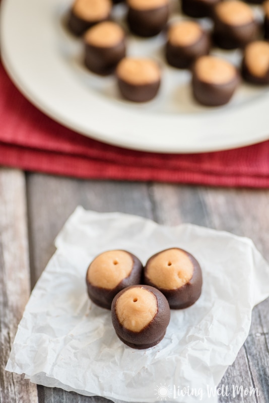 Close up of 3 vegan buckeyes on a napkin with a plate full of them in the background.