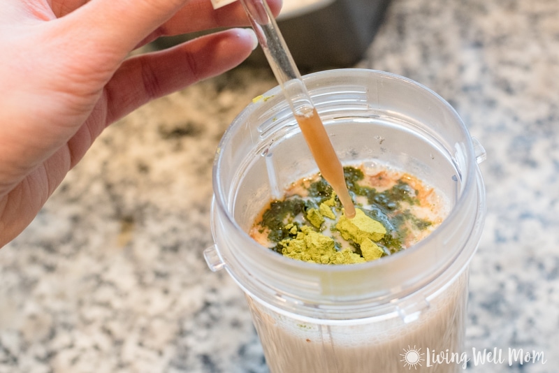 dropperful with stevia adding to plastic blender cup with matcha powder and milk