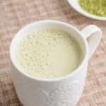 white mug with beige background matcha green tea latte