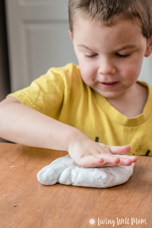 a child presses slimy DIY onto a wooden table