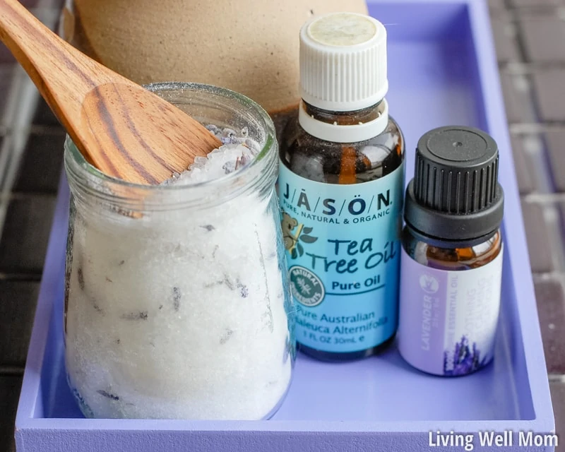 homemade salt foot soak with wooden spoon on purple tray with essential oils