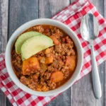 Beanless Turkey & Sweet Potato Chili in a bowl on checkered napkins with a spoon