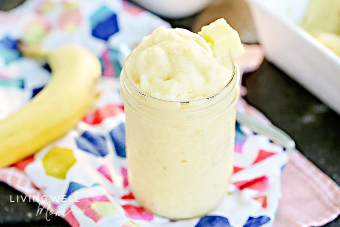 A cup of Healthy Dole Whip ice cream with a chunk of pineapple on the rim of the glass. 