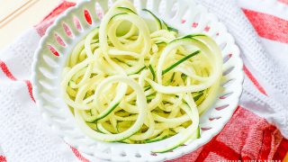 A close up of zucchini noodles on white plate