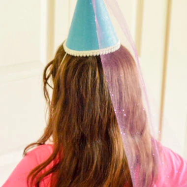 a girl with long brown hair and blue princess hat