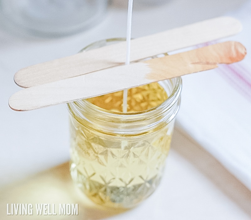 popsicle sticks being used to hold up the wick in DIY citronella candles